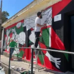 Miembros de La Máquina Creativa y Puerto Real por Palestina pintando un mural.