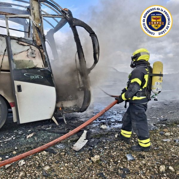 Miembros de los bomberos sofocando el incendio del autobús siniestrado.
